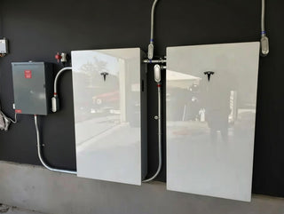 Two Tesla battery units mounted on a wall with visible branding.